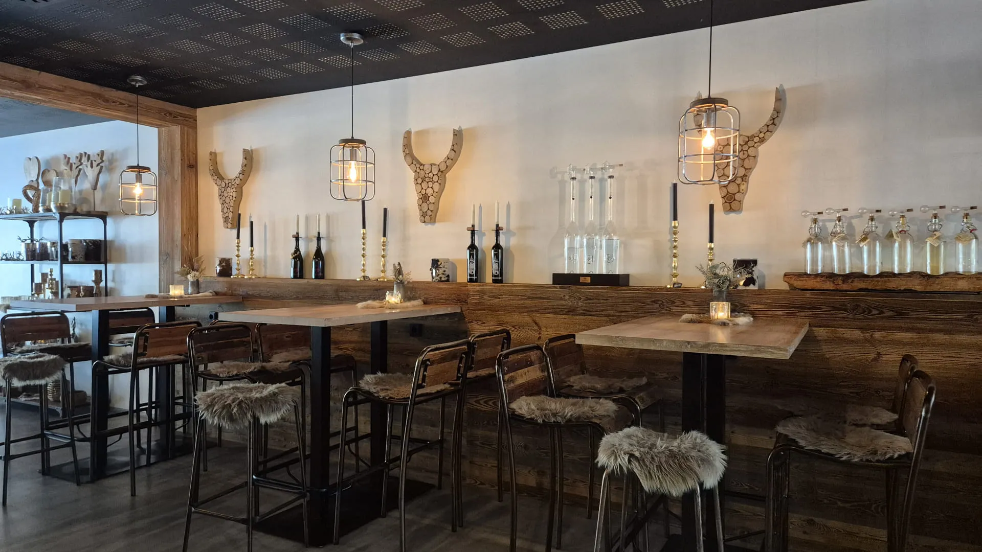 Gemütliche Bar mit Holzmöbeln und dekorativen Geweihen an der Wand.