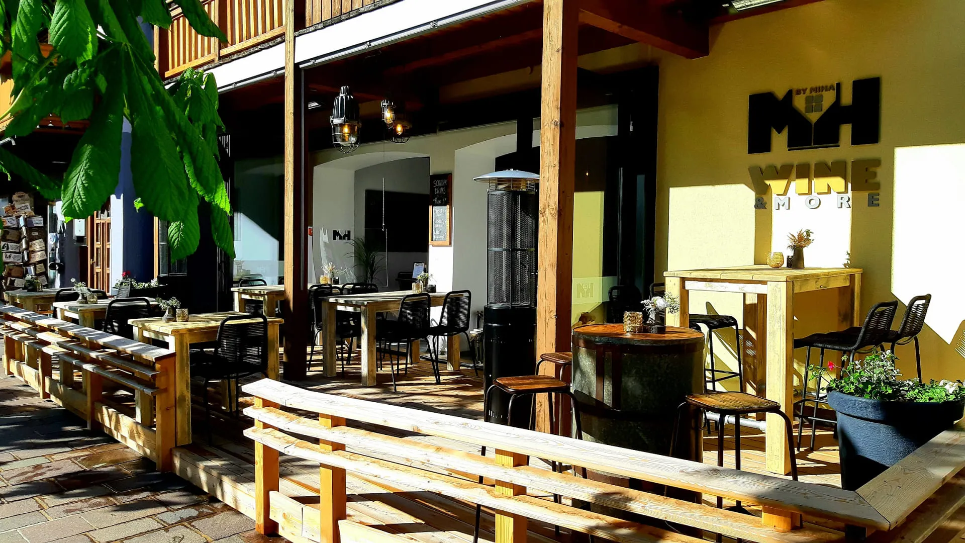 Außenbereich des Geschäfts Terrasse Wine & More mit Tischen und Pflanzen